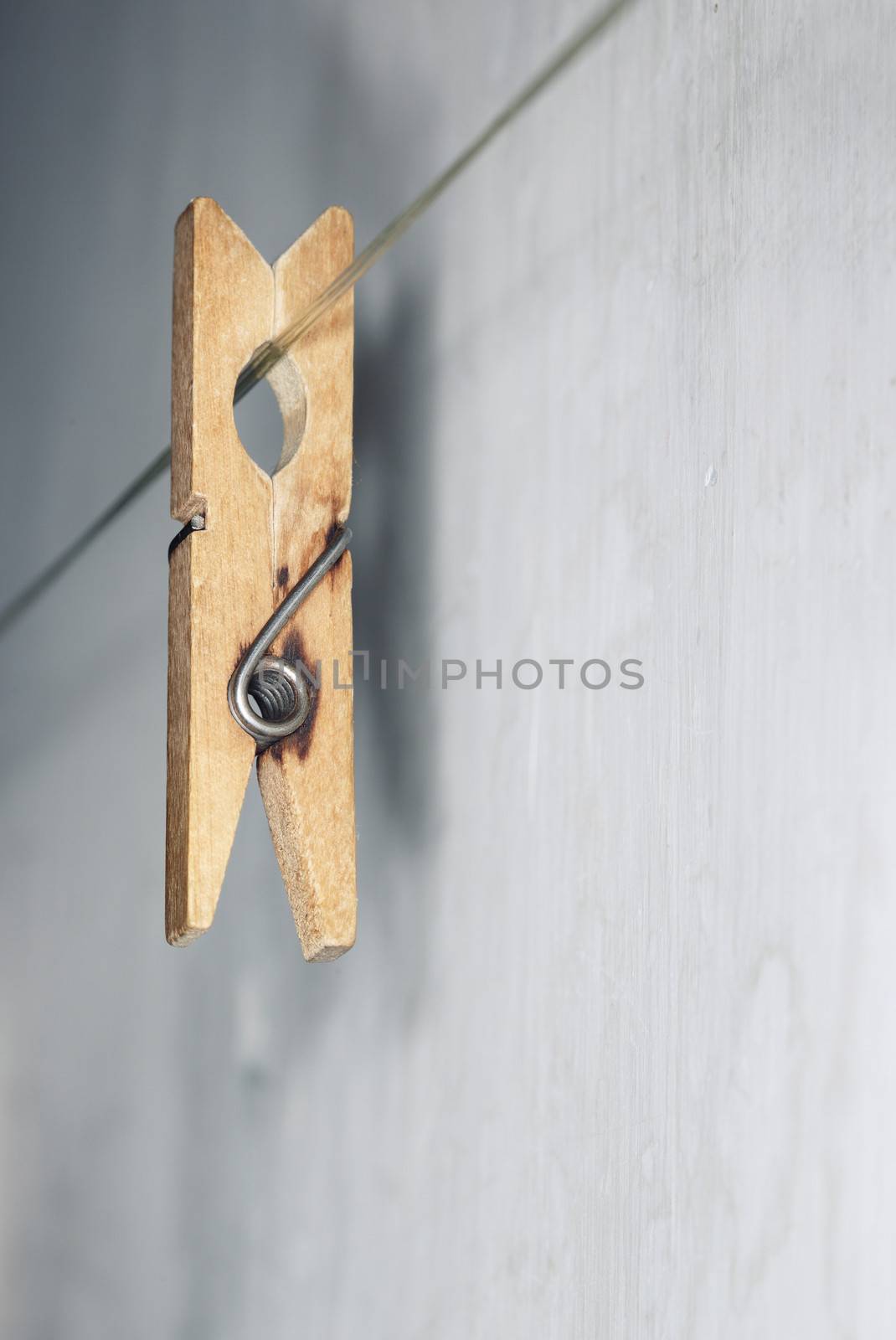 Close-up vertical photo of the old wooden clothes pin hanged on a clothes-line