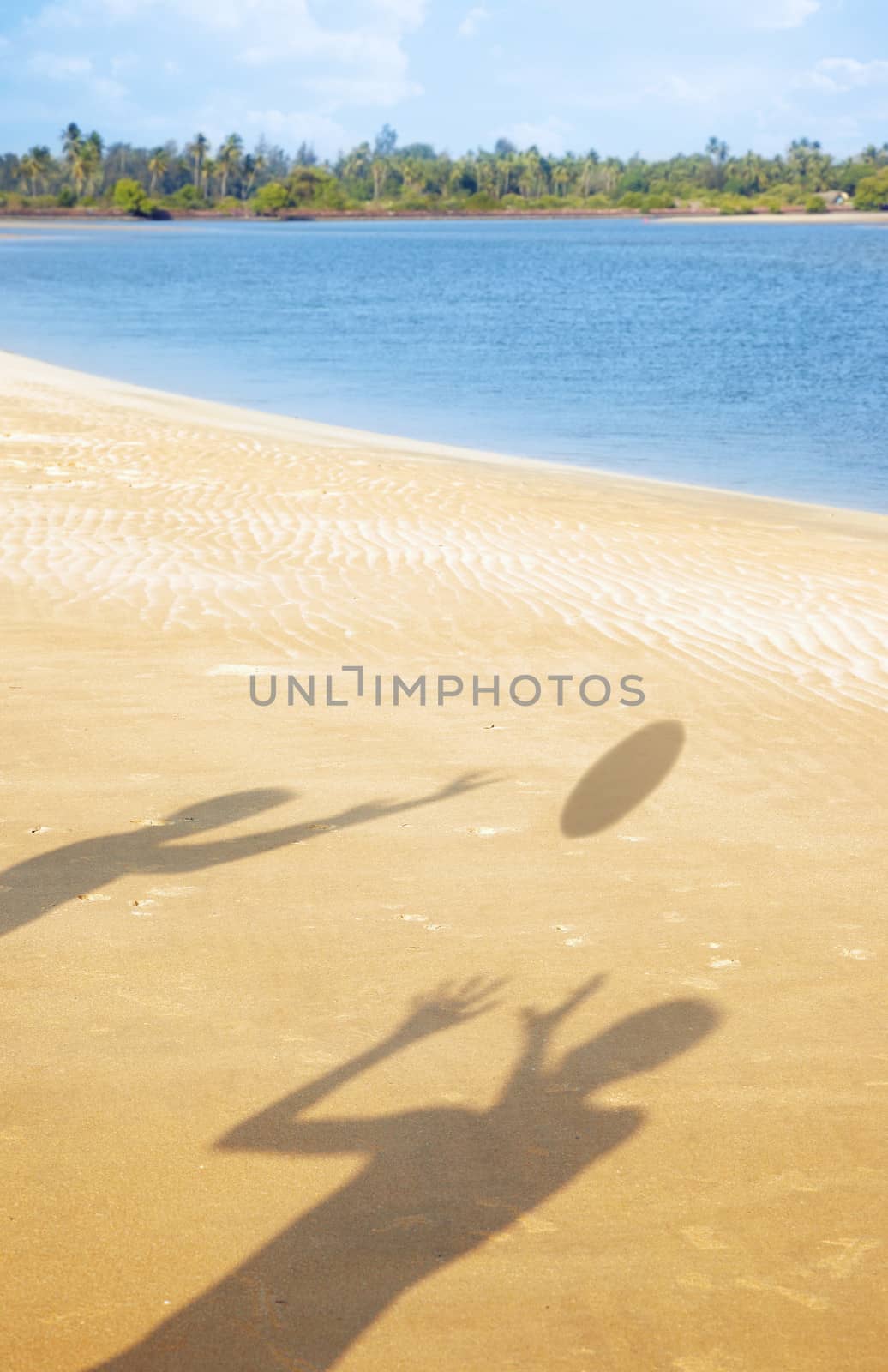 Shadows of two people playing with ball at the summer beach. Vertical photo with vibrant colors