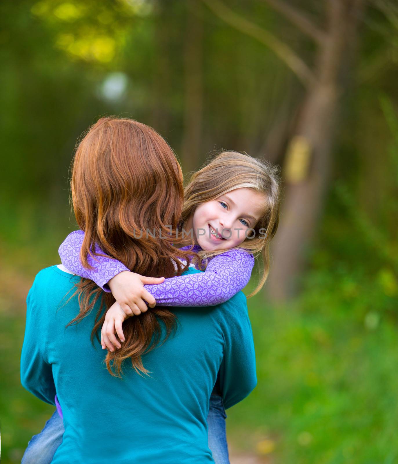 Mum holding daughter kid girl in her arms rear view smiling in outdoor