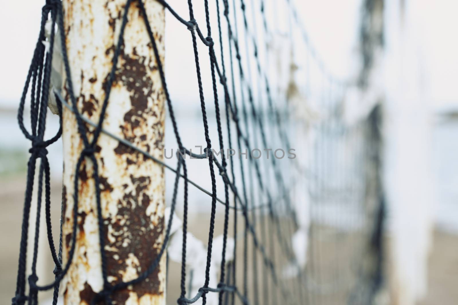 Old net attached to the poles at the beach. Shallow depth of field added for more natural view