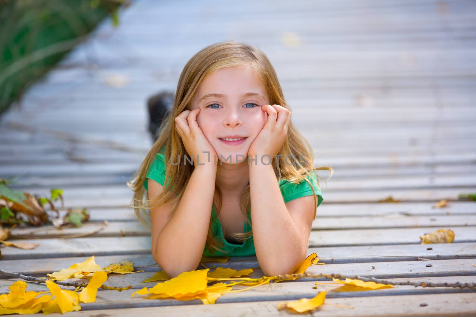 Kid girl in autumn wood deck with yellow leaves outdoor by lunamarina