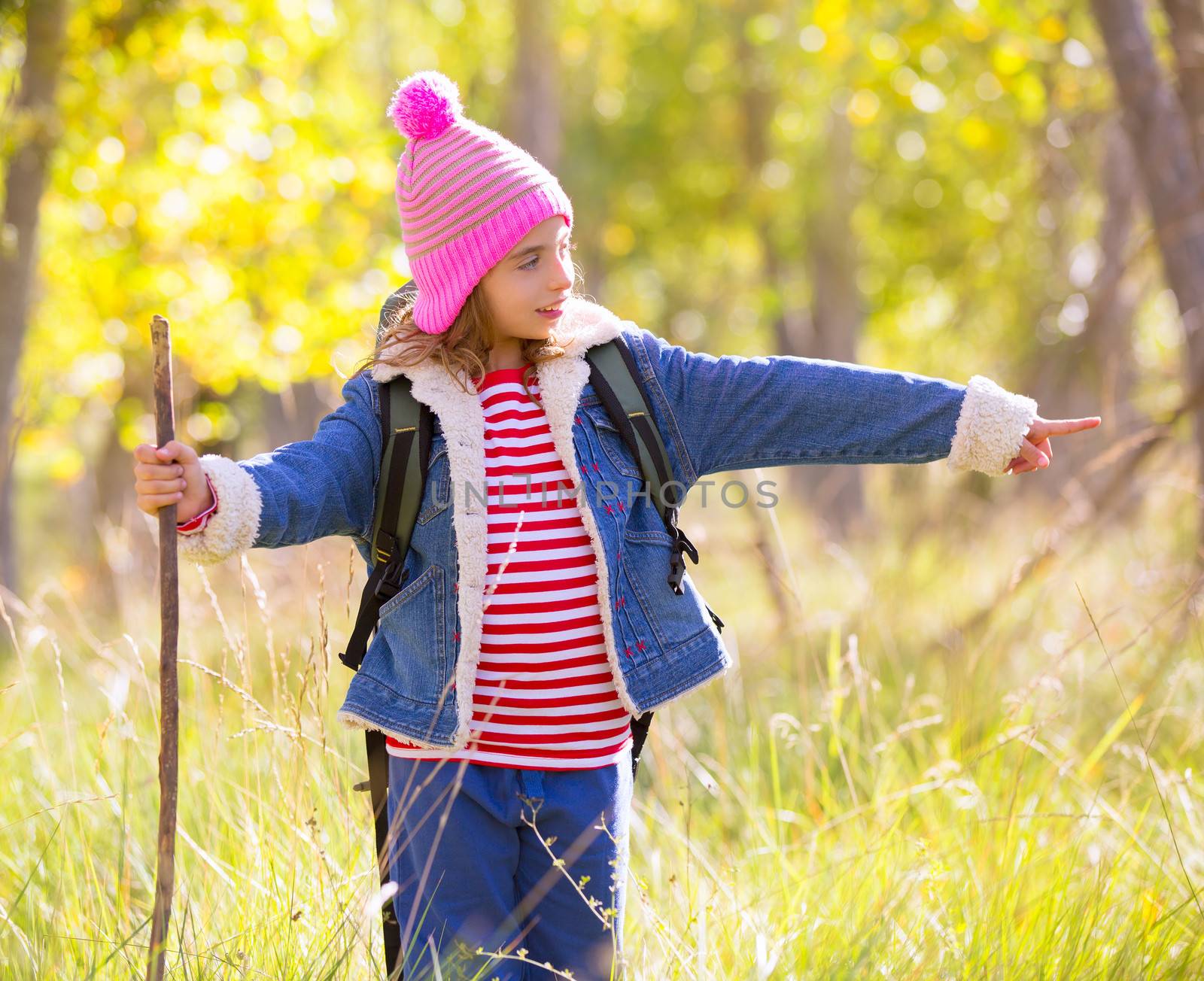 Hiking kid girl with backpack pointing finger in autum forest by lunamarina