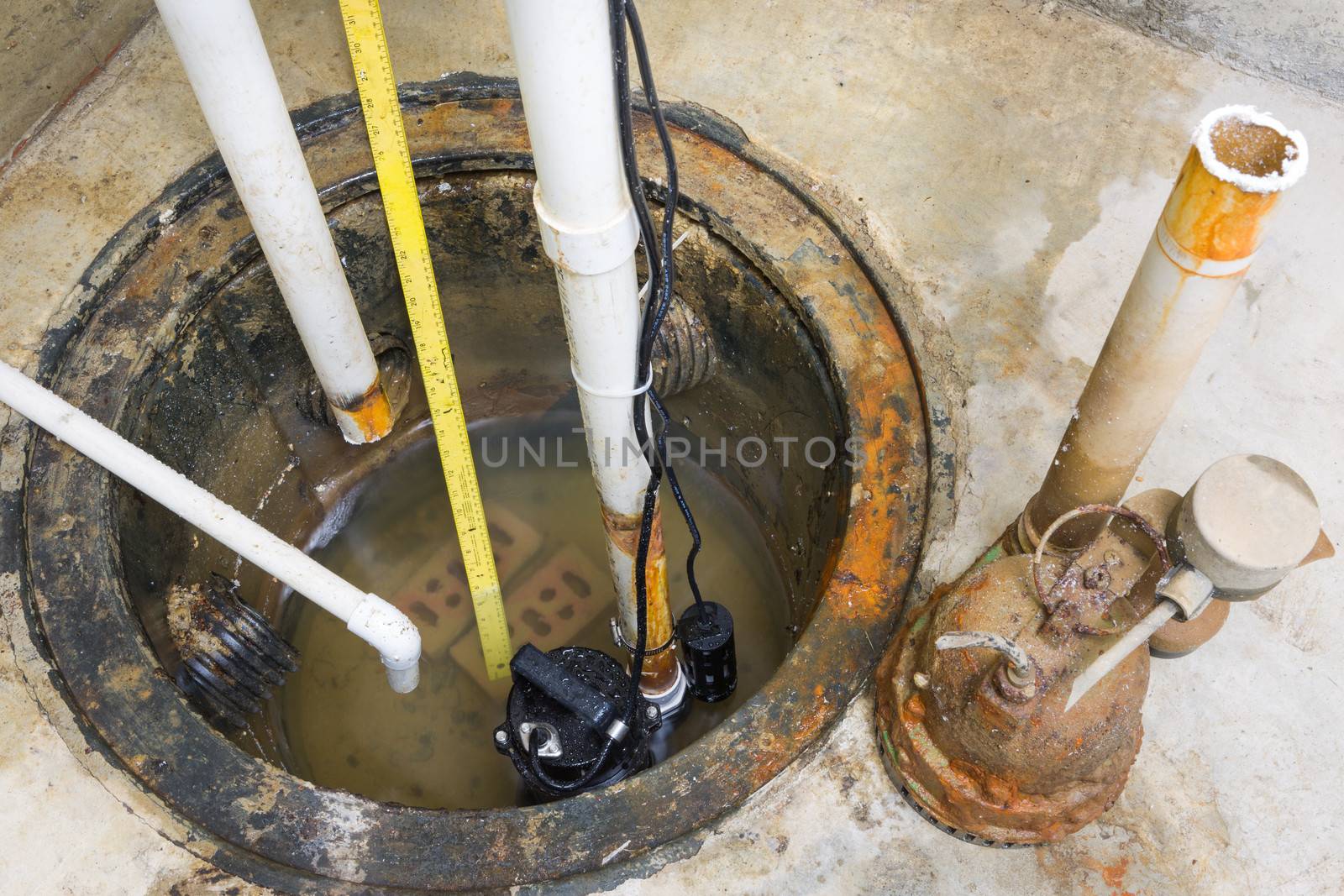 Installation of a new sump pump and the removal of the old obsolete rusty one with a high angle view of the pumps, pit and pipes