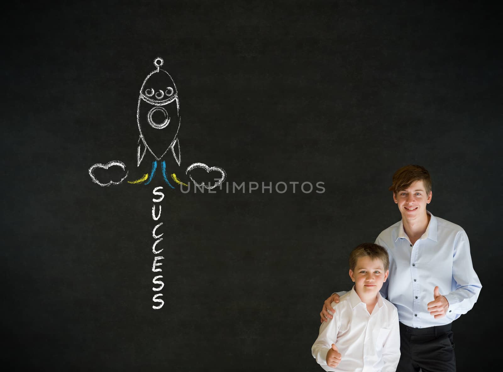 Thumbs up boy dressed up as business man with teacher man and chalk success rocket on blackboard background