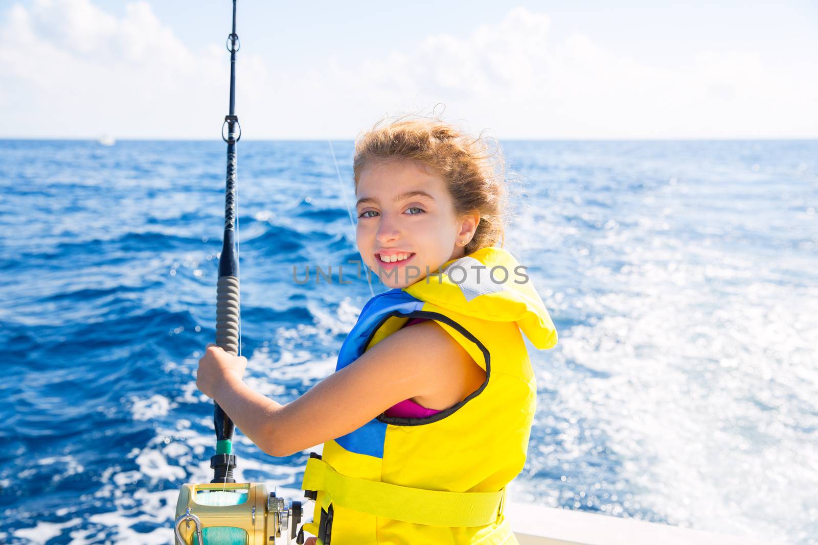 blond kid girl fishing trolling at boat with rod reel and yellow life jacket