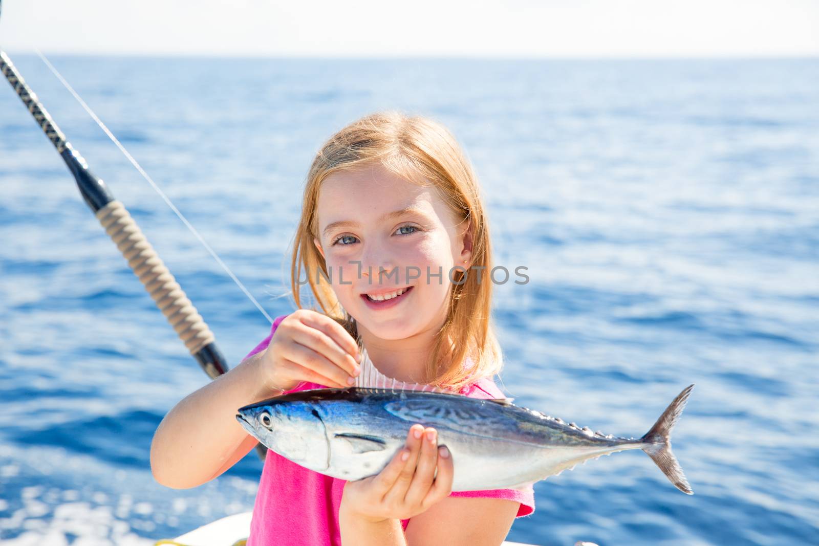 Blond kid girl fishing tuna little tunny happy with catch by lunamarina