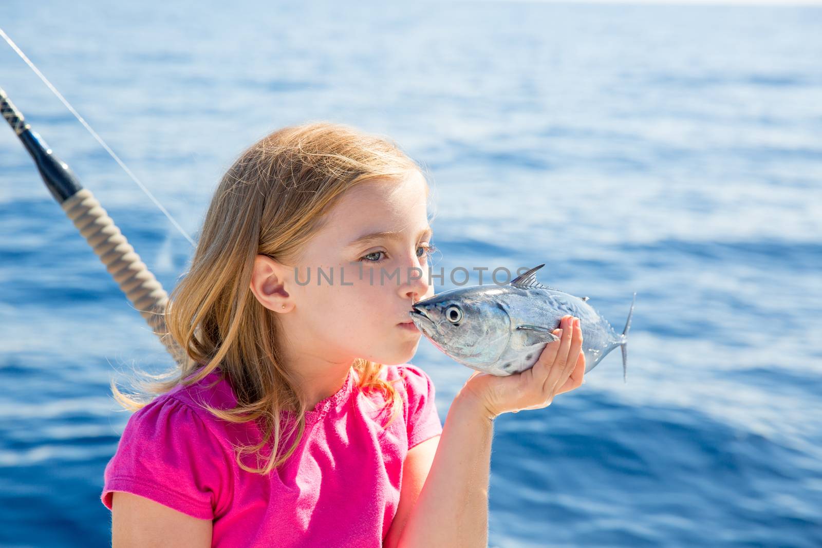 Blond kid girl fishing tuna little tunny kissing fish for release due tiny size