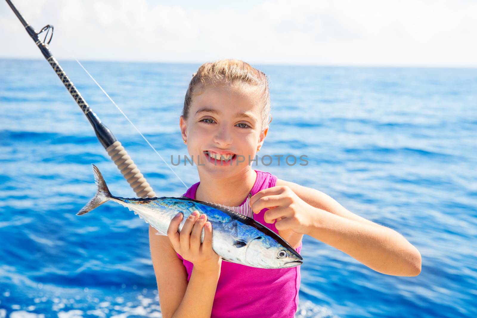 Kid girl fishing tuna little tunny happy with trolling fish catch on boat deck