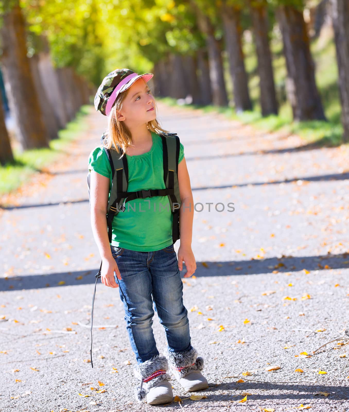 Blond explorer kid girl walking with backpack in autumn trees by lunamarina