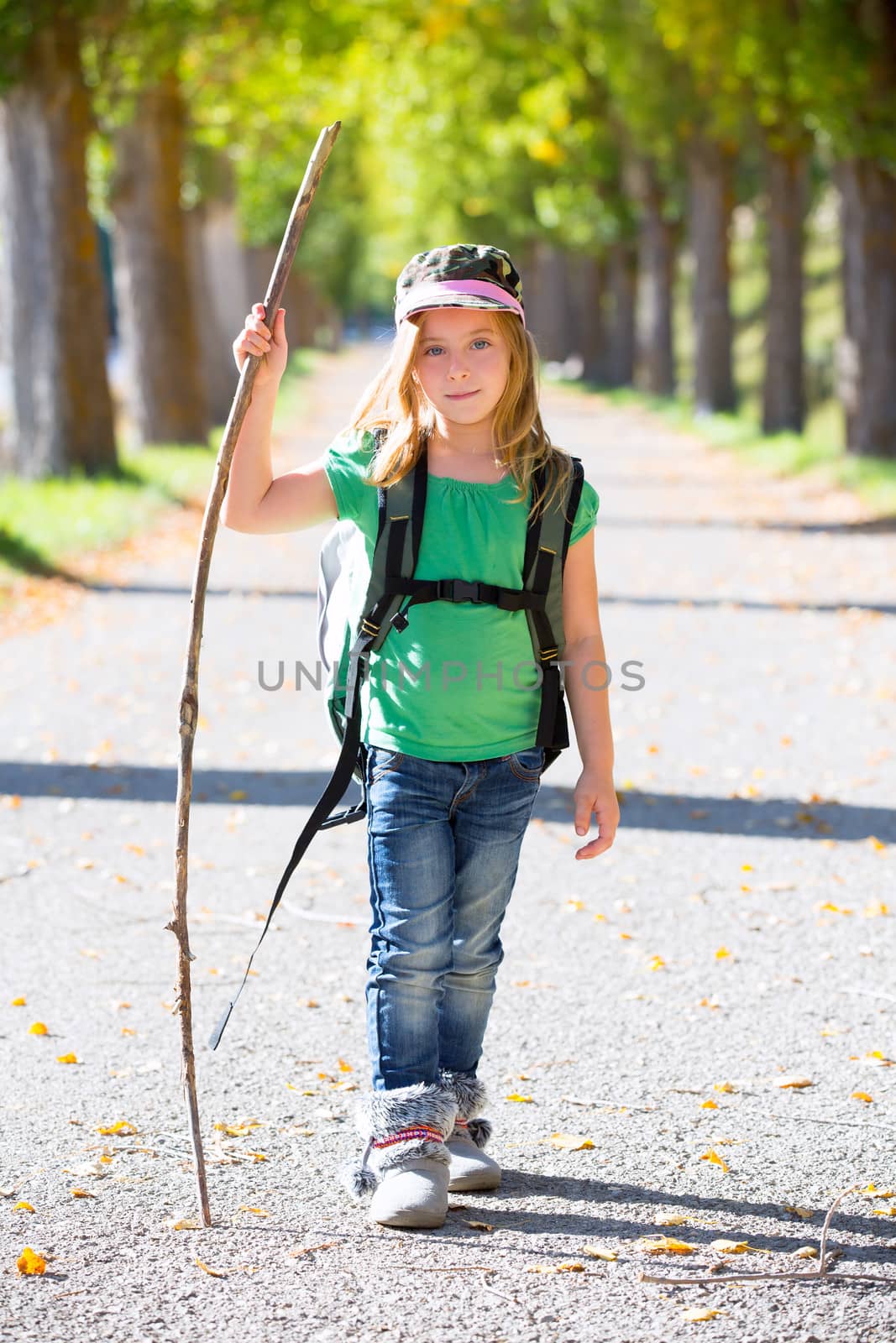 Blond explorer kid girl walking with backpack in autumn trees by lunamarina