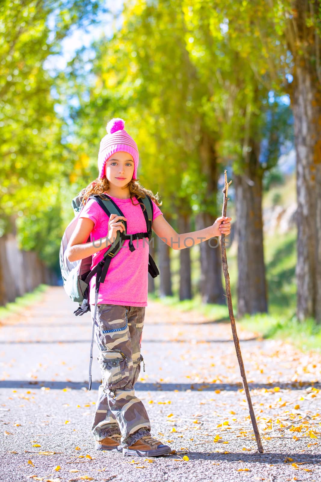 hiking kid girl with walking stick and backpack in autumn by lunamarina