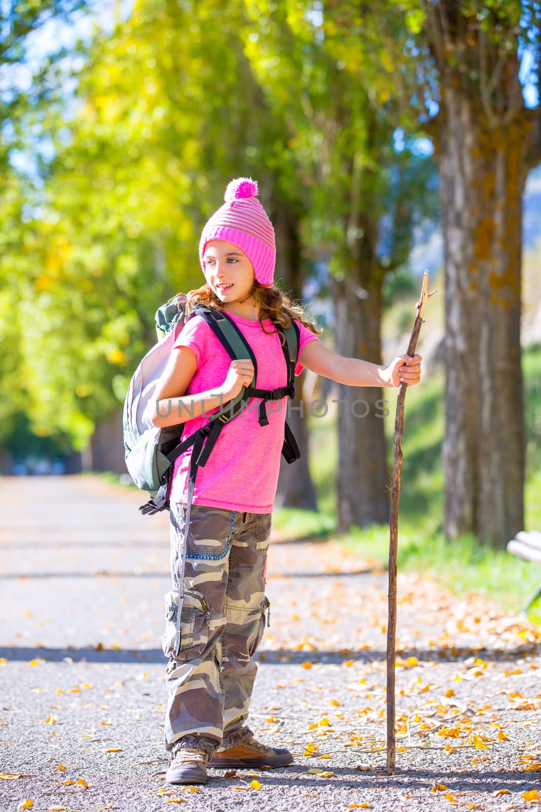 hiking kid girl with walking stick and backpack exploring autumn track and camouflage pants