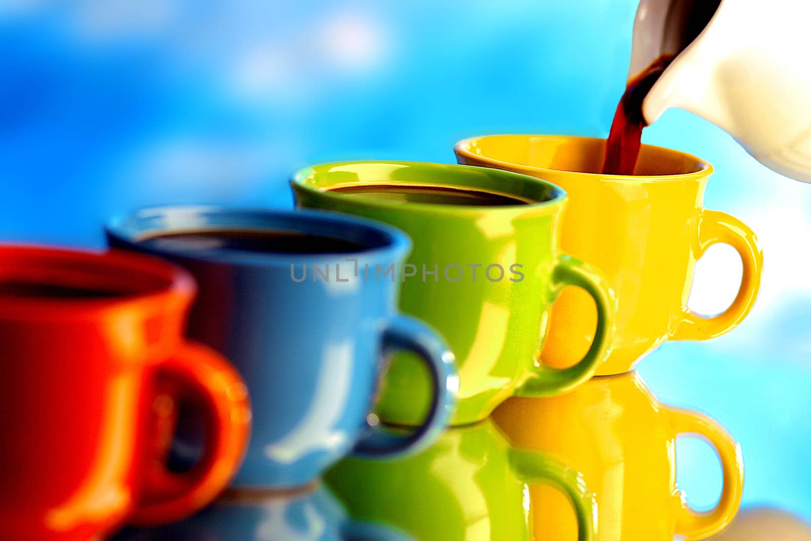 Pouring fresh coffee in various colorful cups.