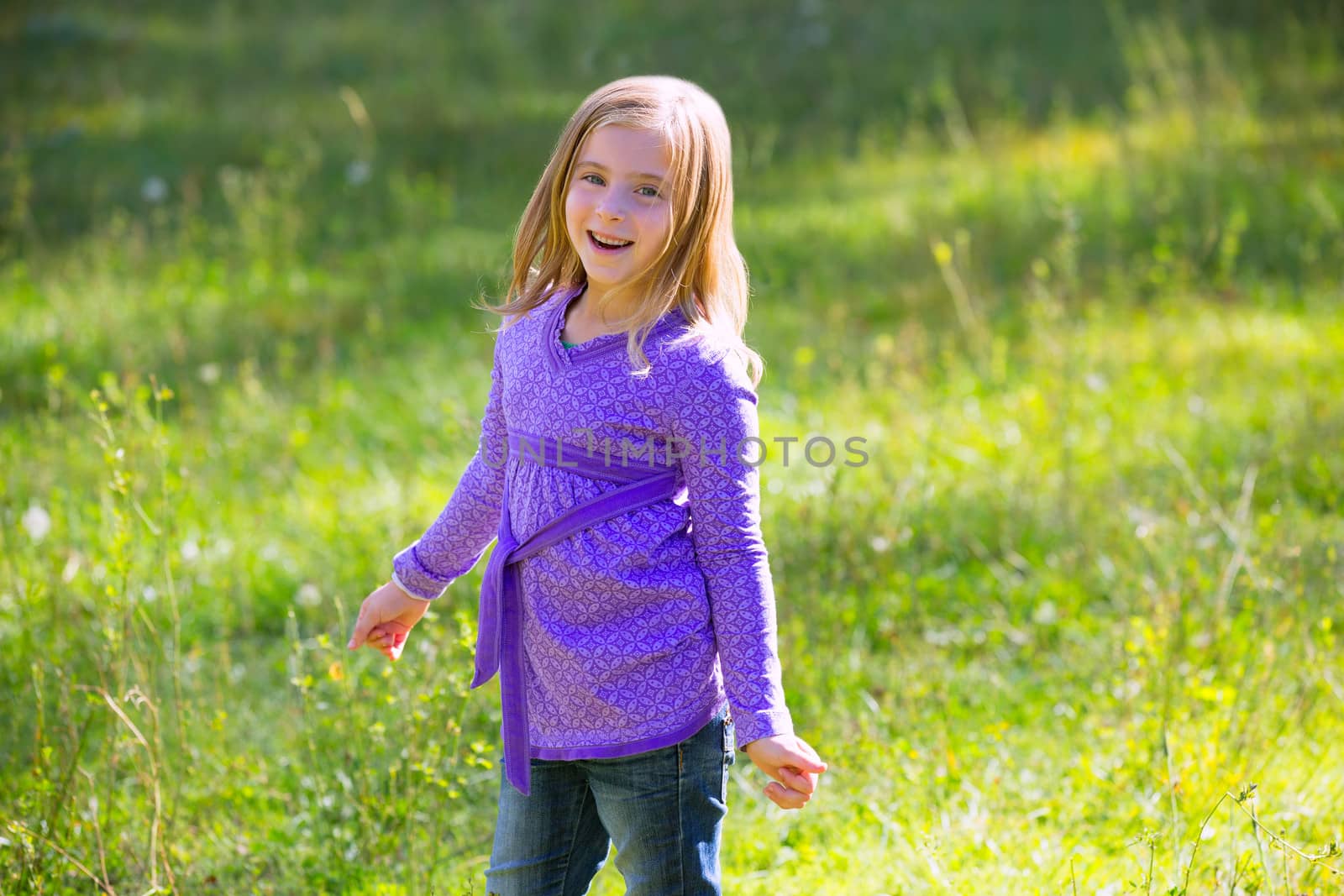 Blond kid girl happy in outdoor green meadow by lunamarina