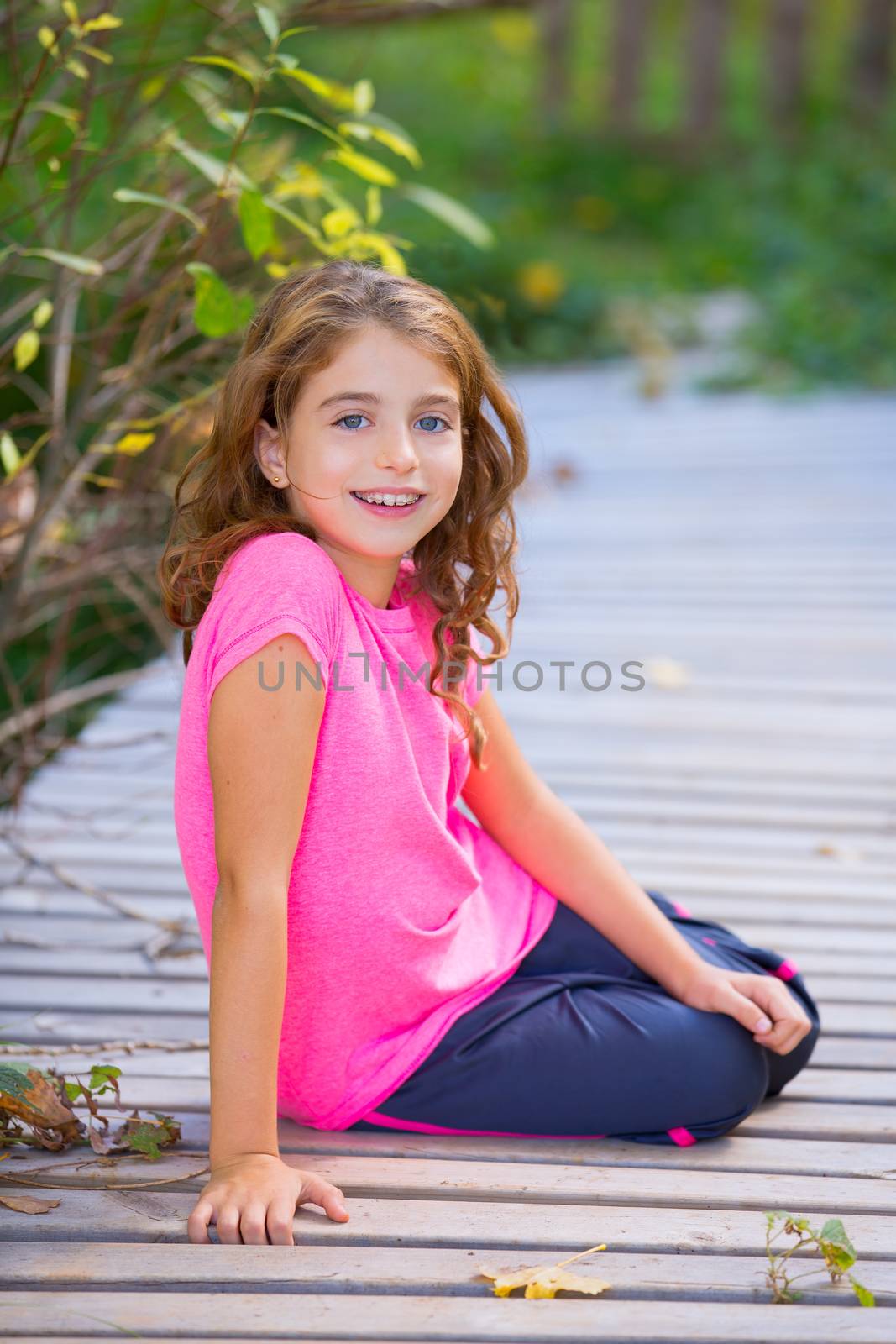 Kid girl in autumn deck smiling with braces teeth apparatus outdoor
