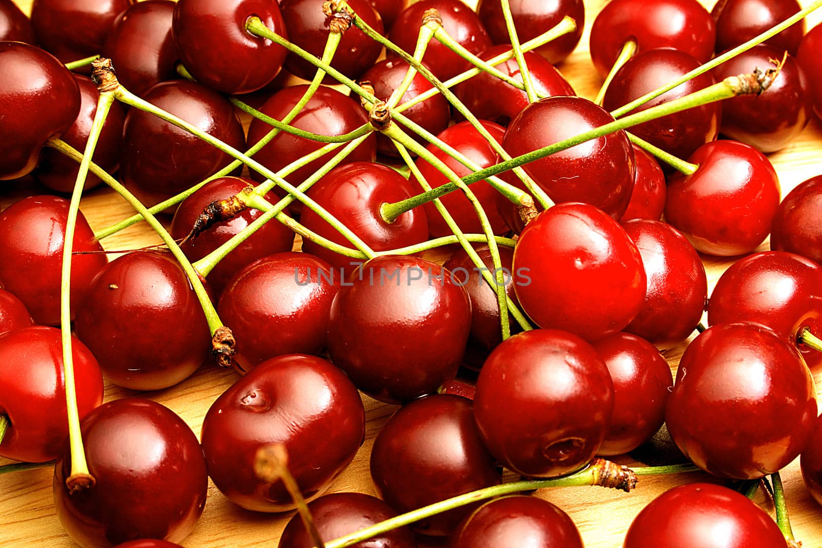 Shining fresh cherries randomly dropped on table.