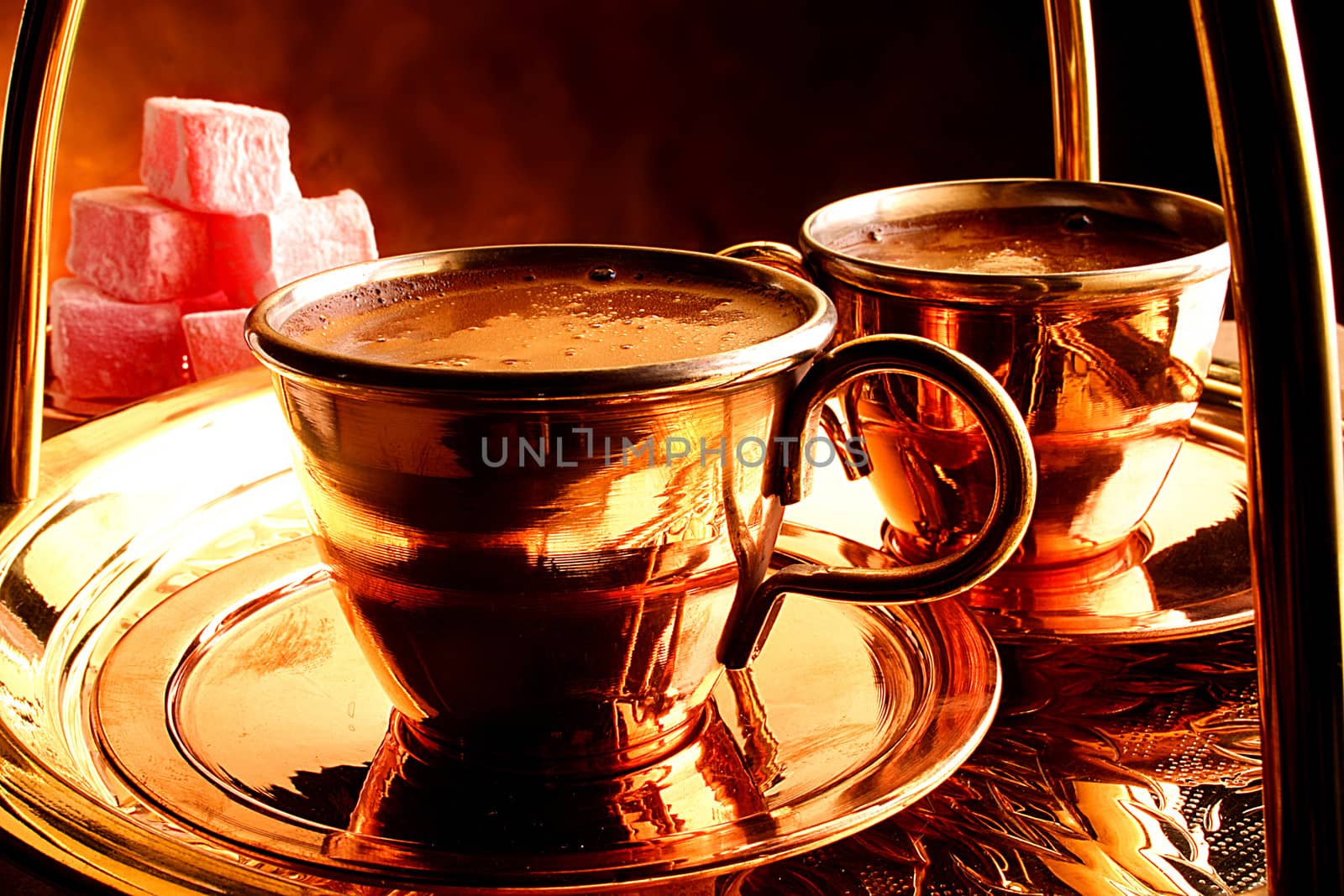Two cups of turkish coffee on a tray with traditional delicacy on the side.