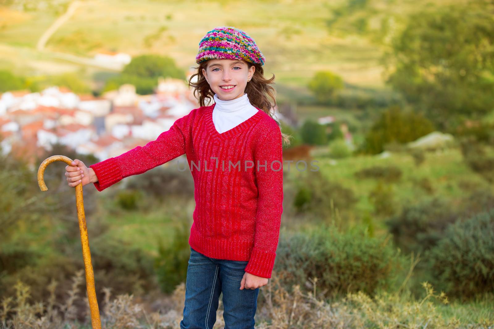 Kid girl shepherdess with wooden baston in Spain village by lunamarina