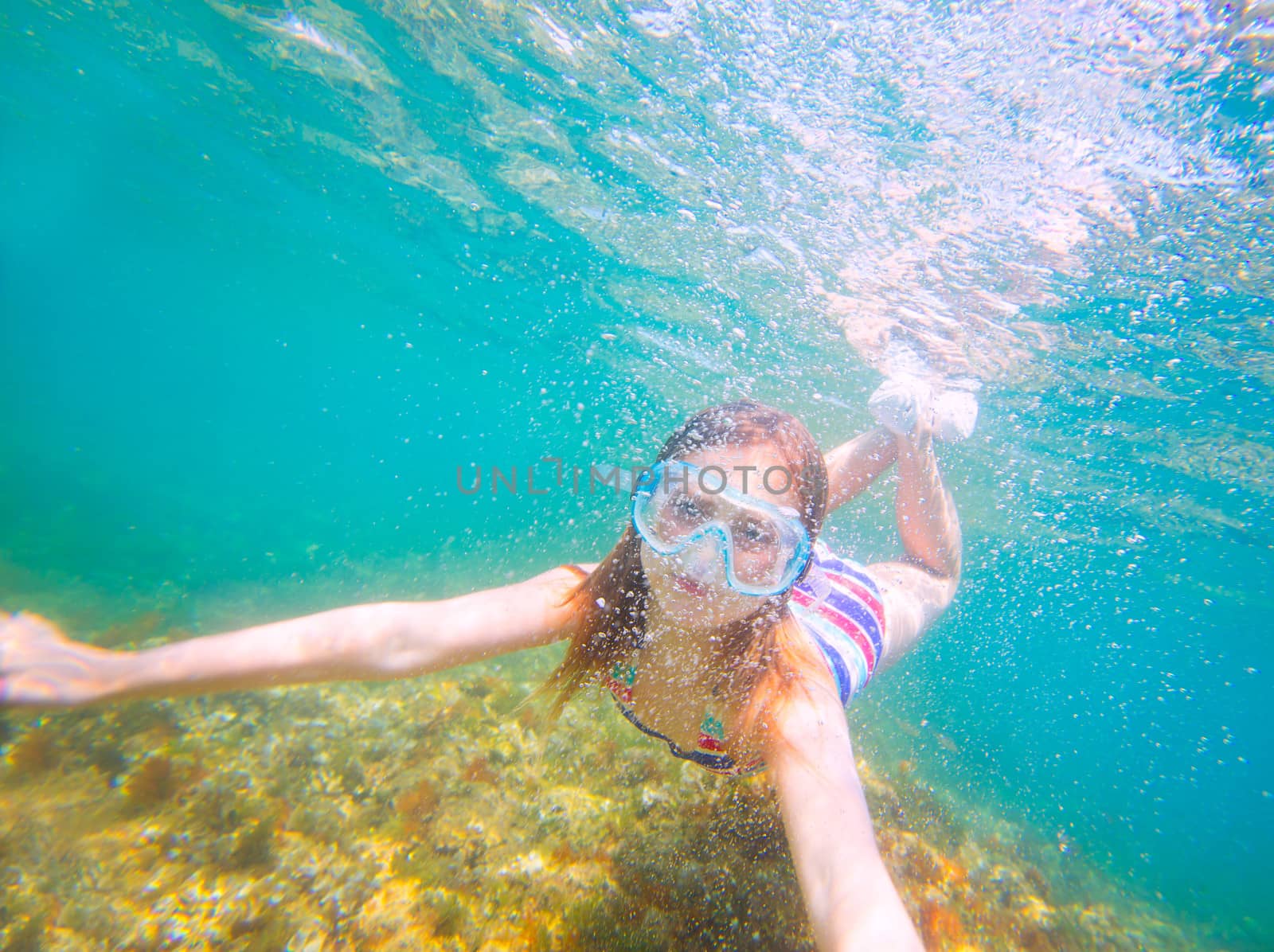 snorkeling blond kid girl underwater with goggles and swimsuit in Mediterranean sea