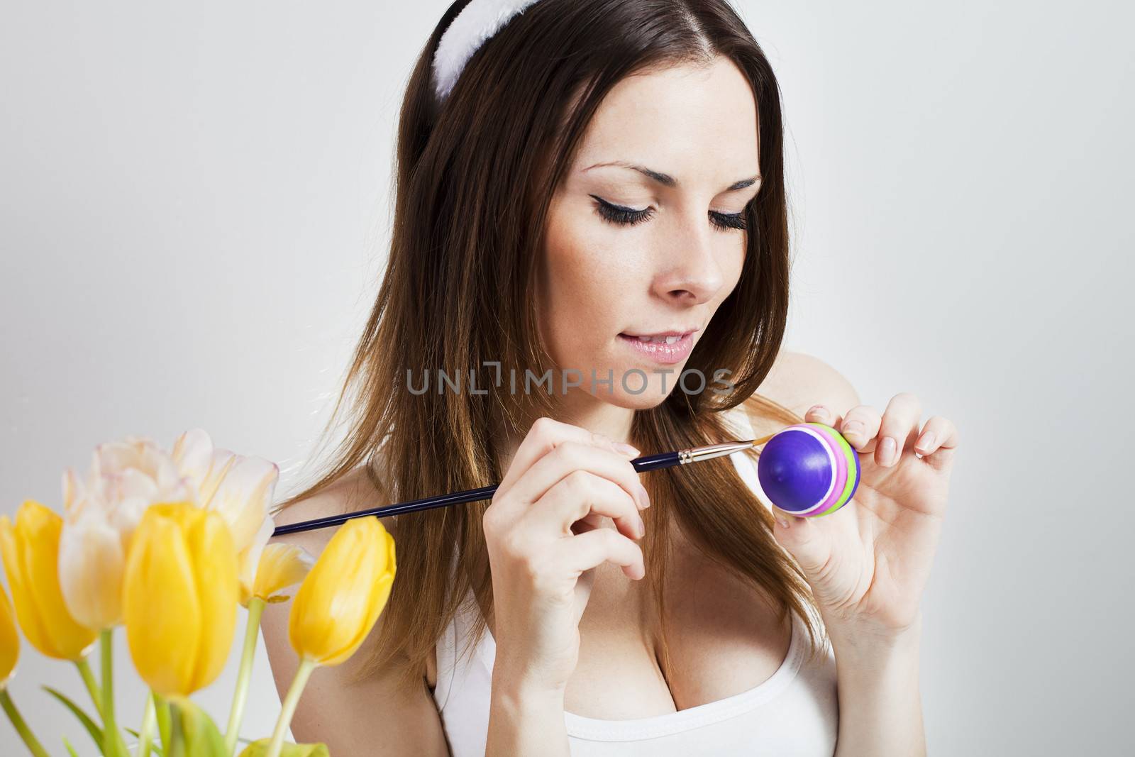 Pretty brunette painting colorful easter eggs in spring