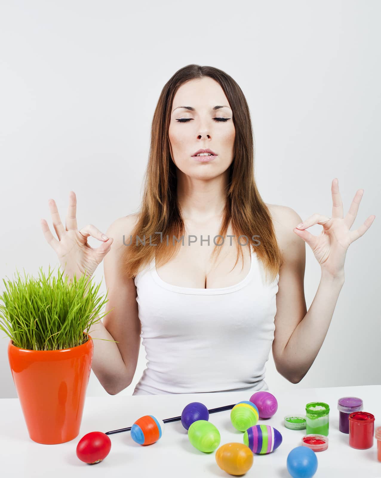 Woman meditating with easter eggs and green grass