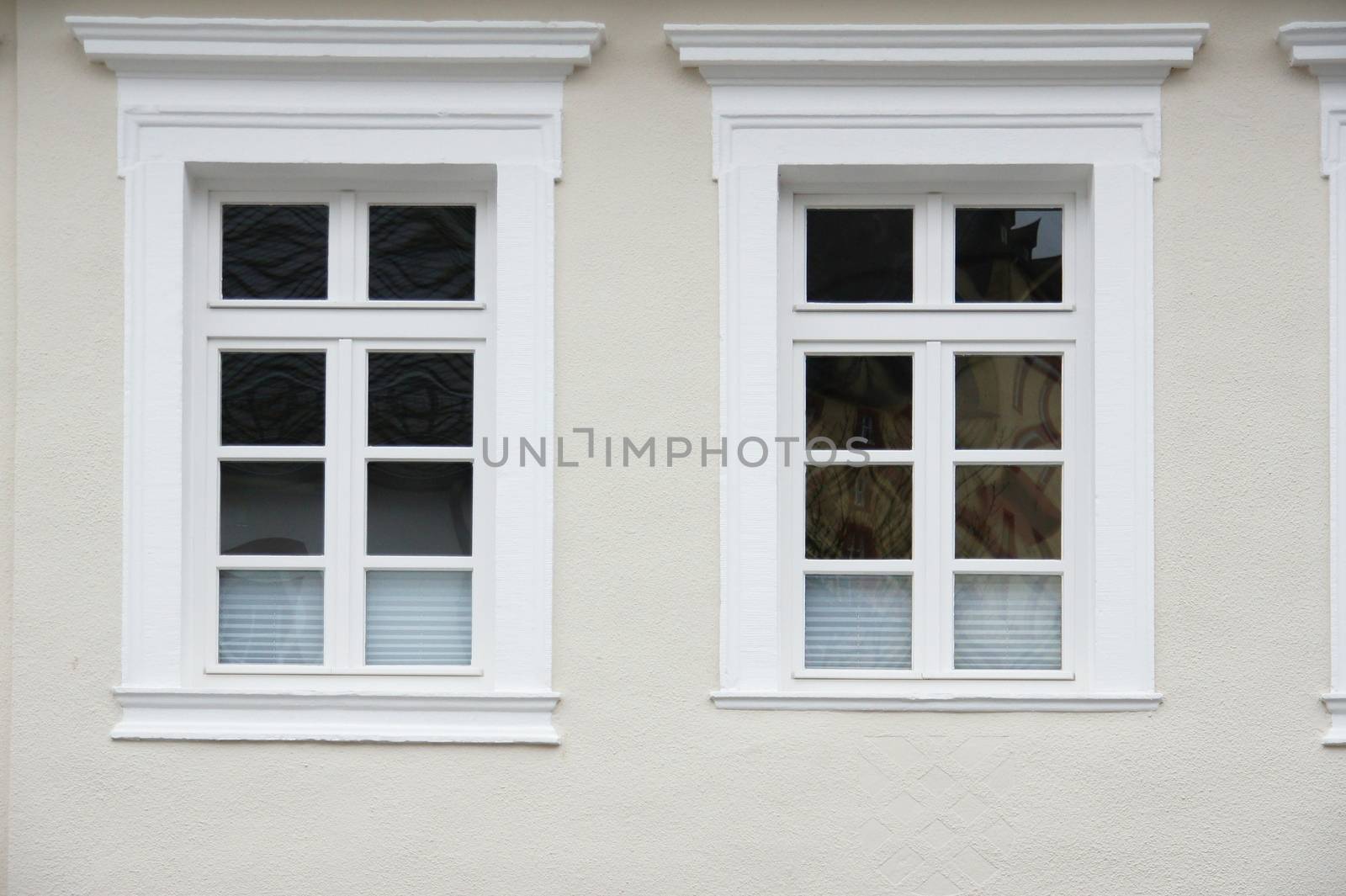 2 fast gleiche Fenster in heller Fassade
