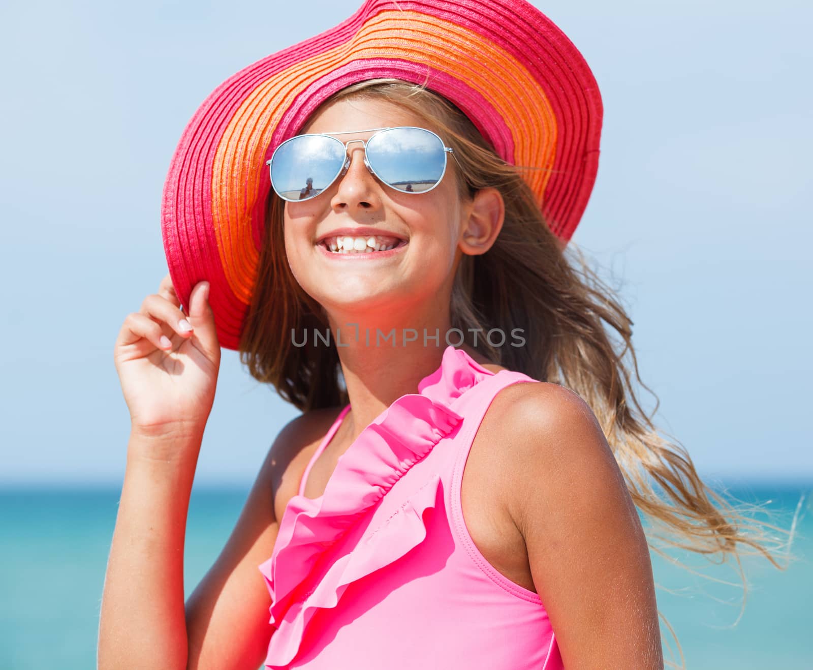 Portrait of beautiful blond girl in hat and sunglasses on background sea and blue sky