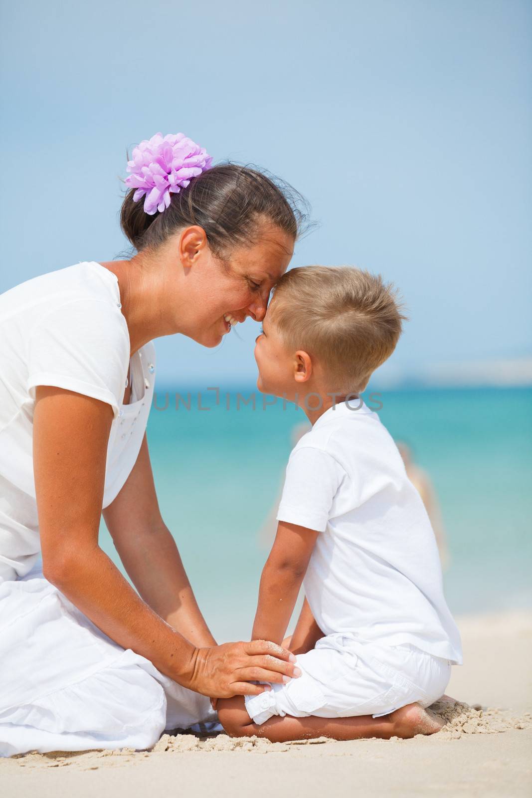 Mother and son having fun on the beach by maxoliki