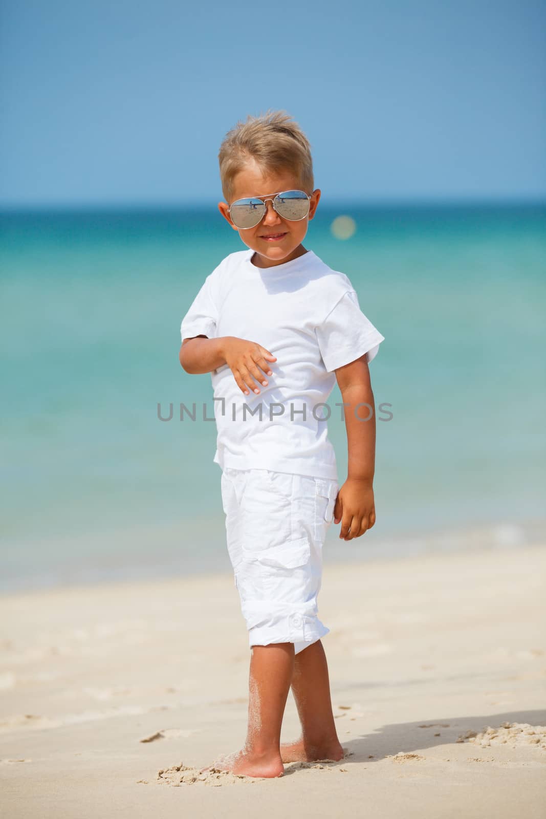 Adorable happy boy in sunglasses on beach vacation