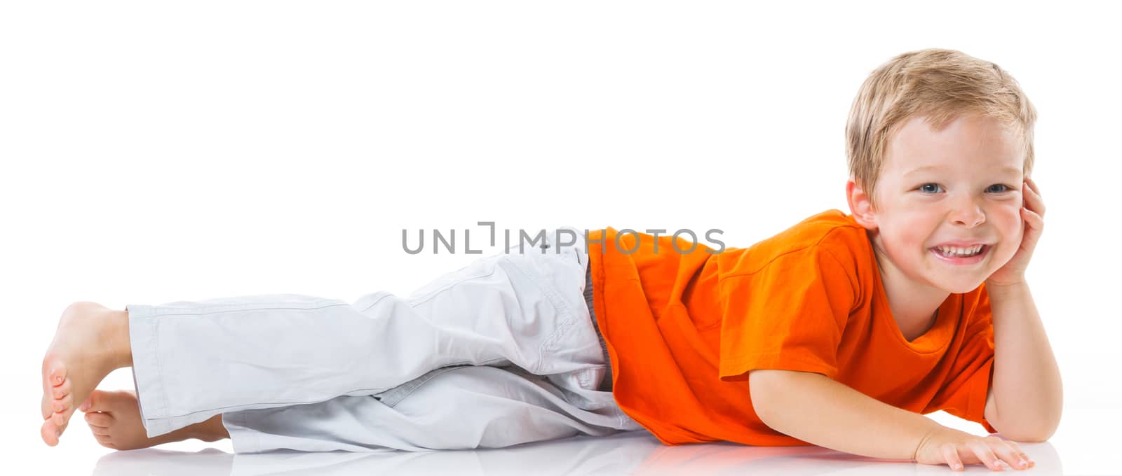 Adorable happy boy lying on the floor in studio. Isolated of white background.