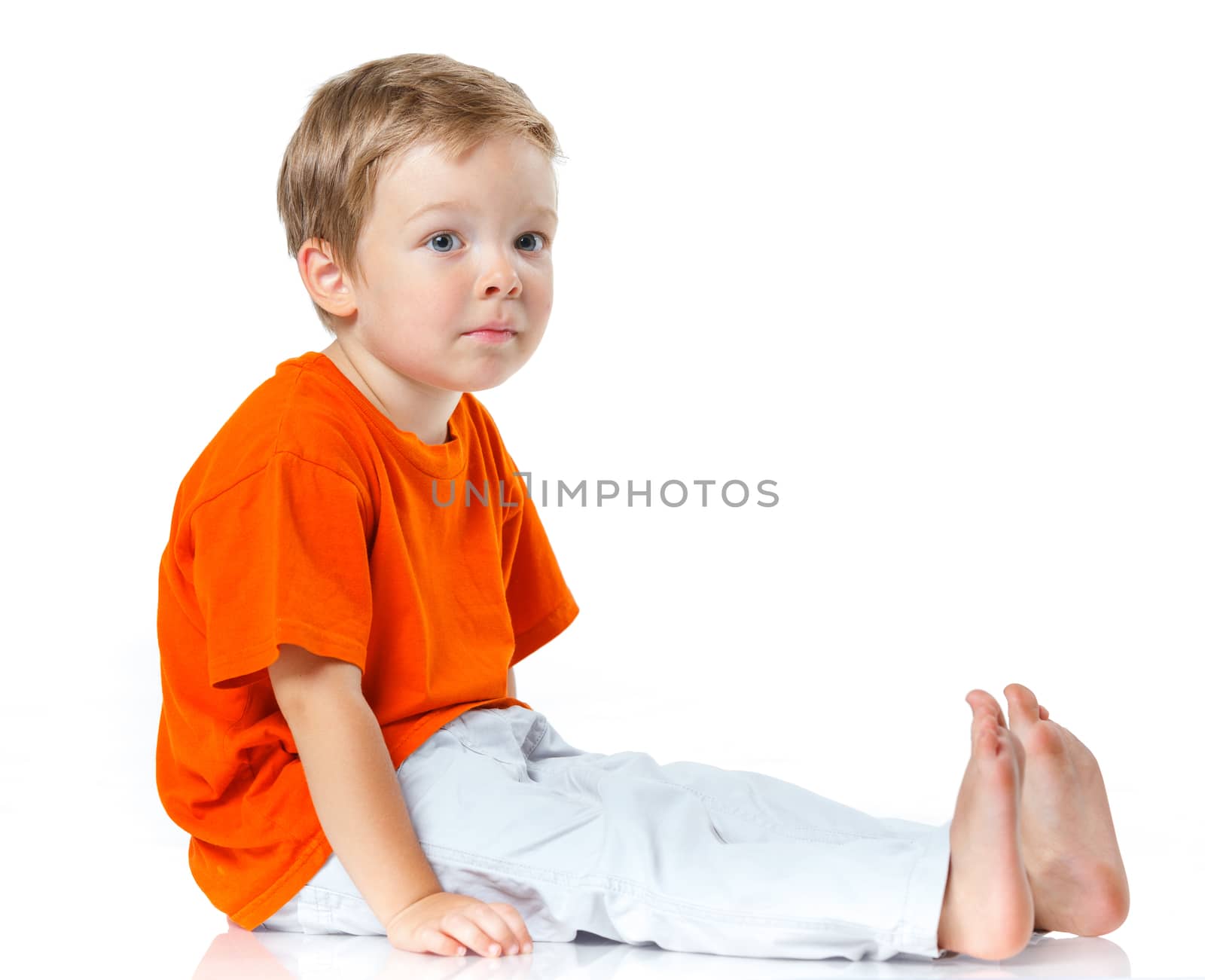 Adorable happy boy sitting on the floor in studio. Isolated of white background.