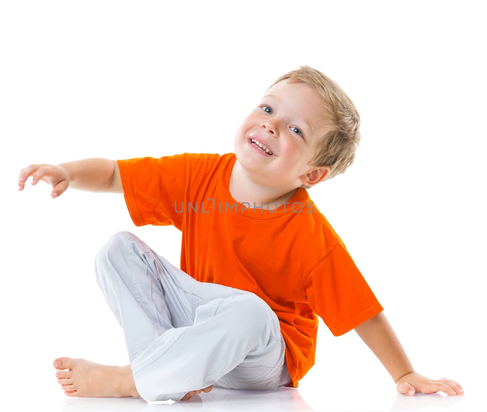 Adorable happy boy sitting on the floor in studio. Isolated of white background.
