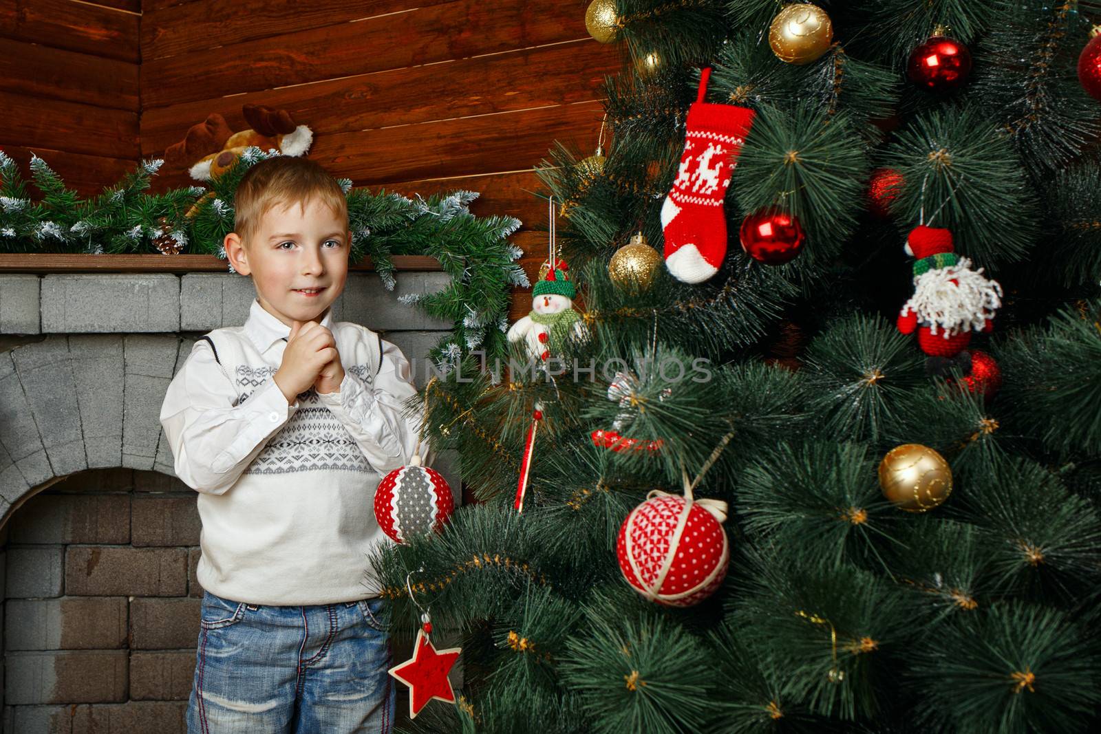 Boy decorates Christmas tree with festive toys and garlands