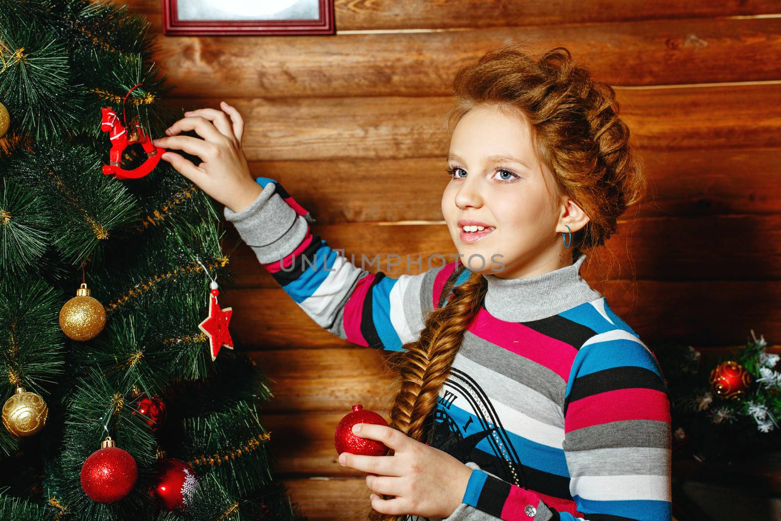 Little girl with plait Christmas tree decorates toys