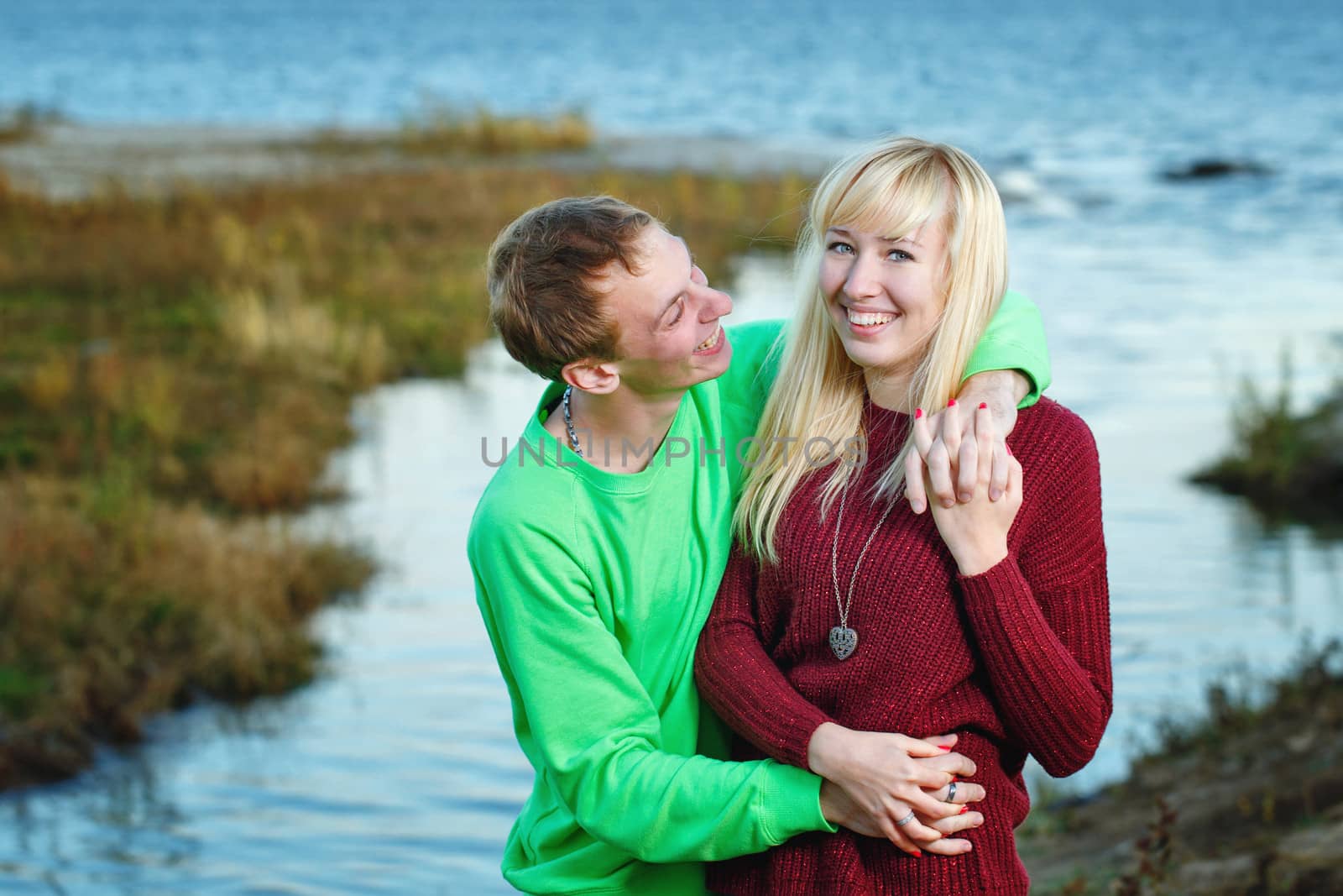 Young couple tenderly and lovingly embrace each other on banks of river