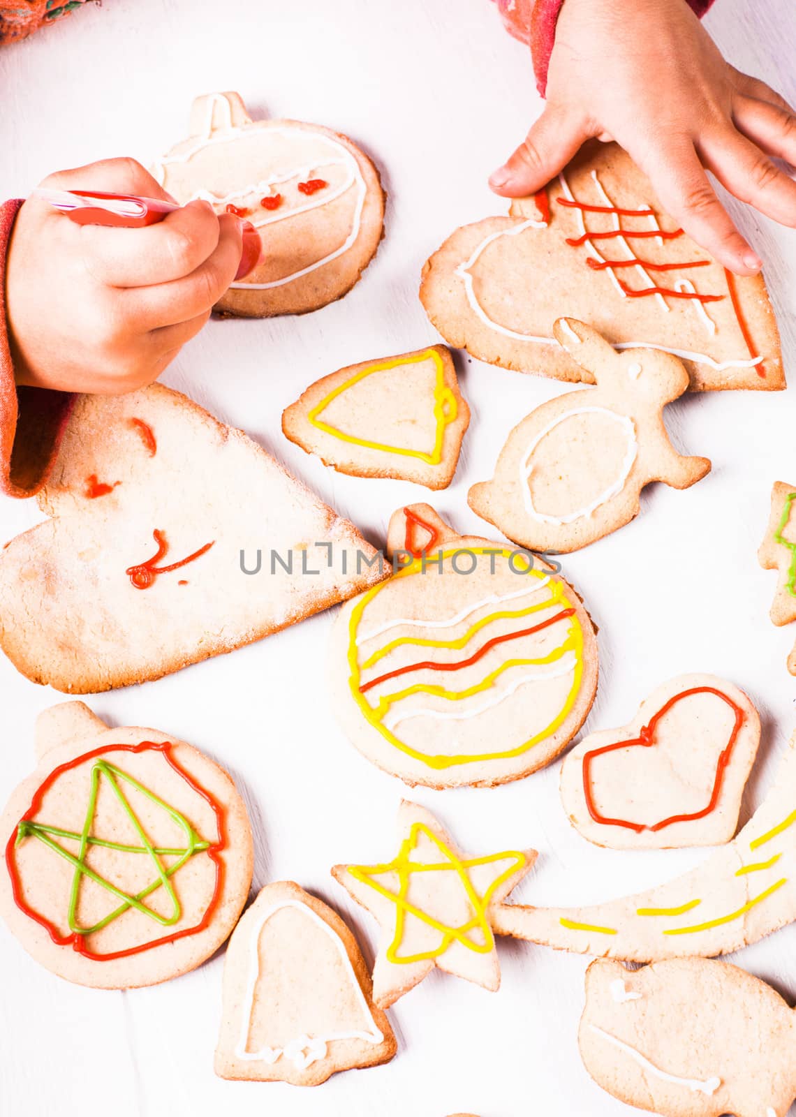 Hands of little girl, who draws on gingerbread cookies