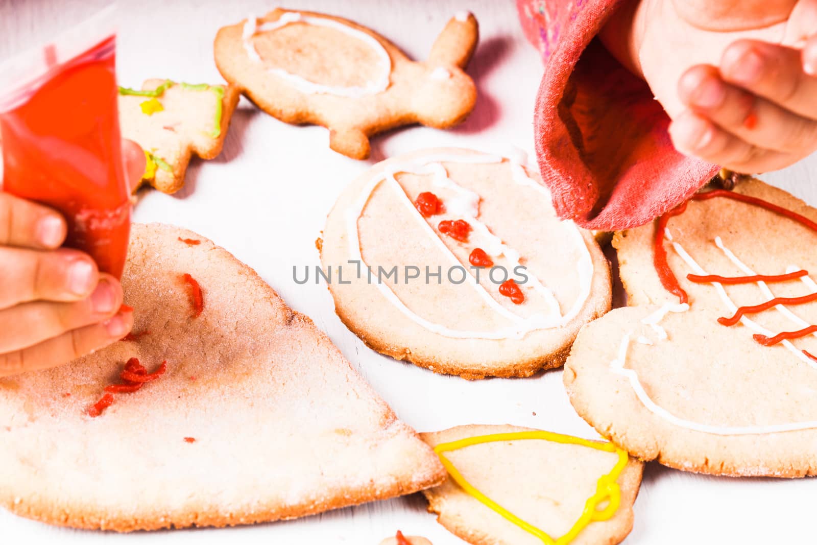 Hands of little girl, who draws on gingerbread cookies