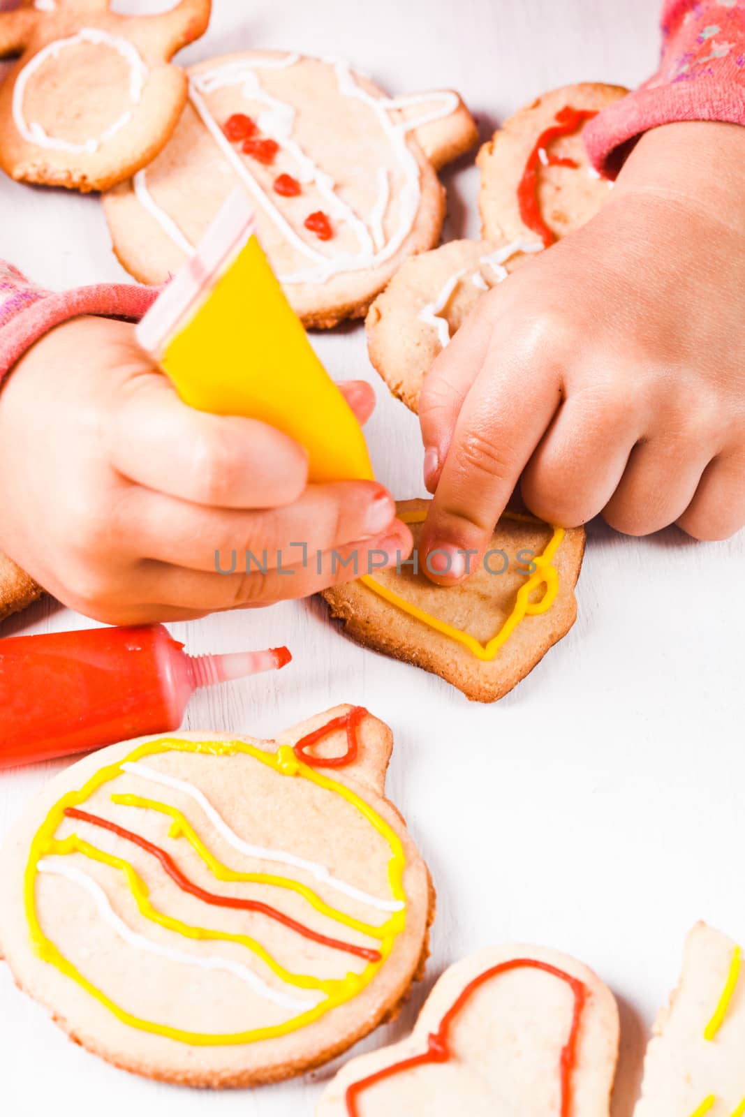 Hands of little girl, who draws on gingerbread cookies