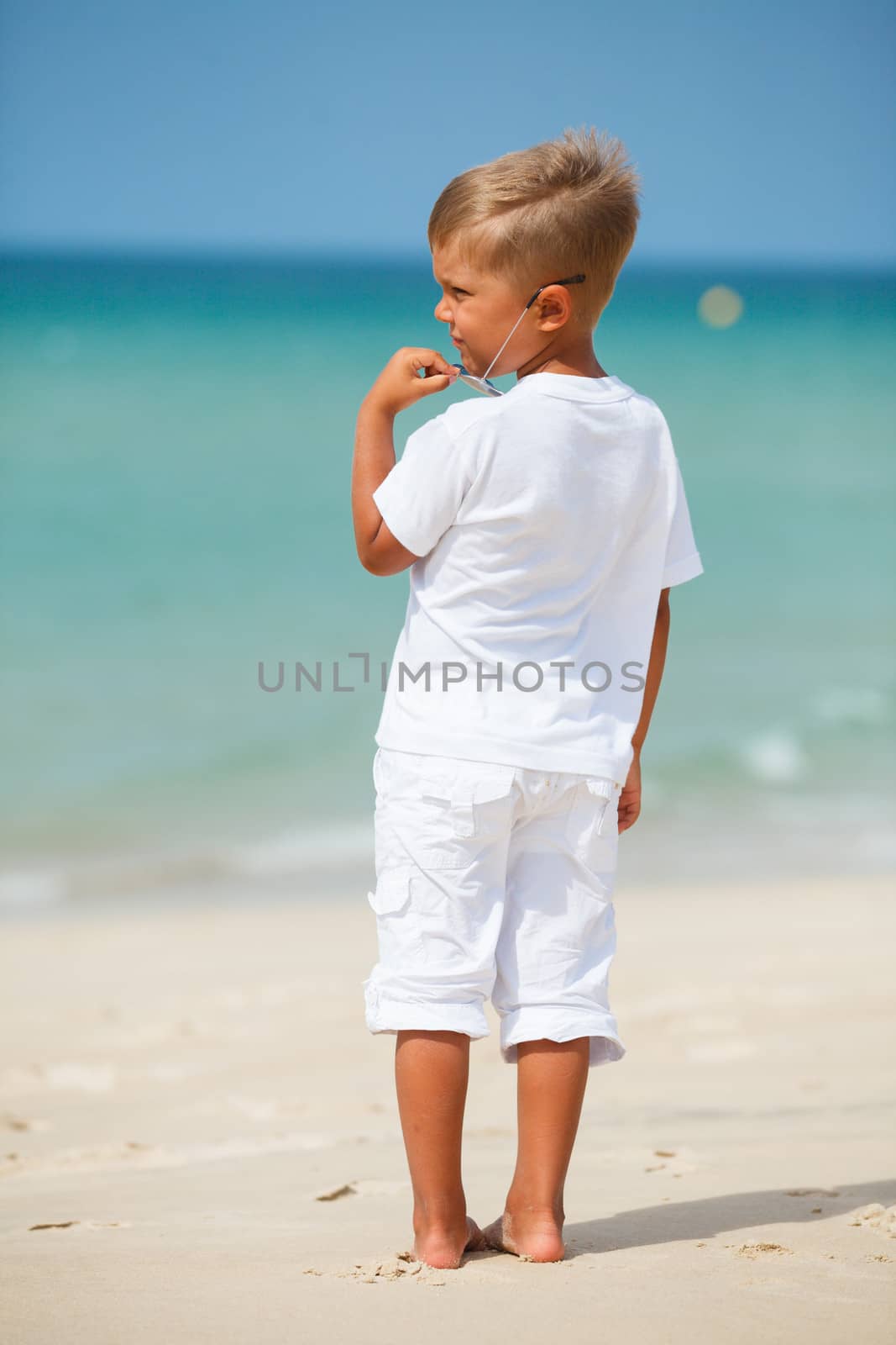 Back view of adorable cute boy on beach vacation
