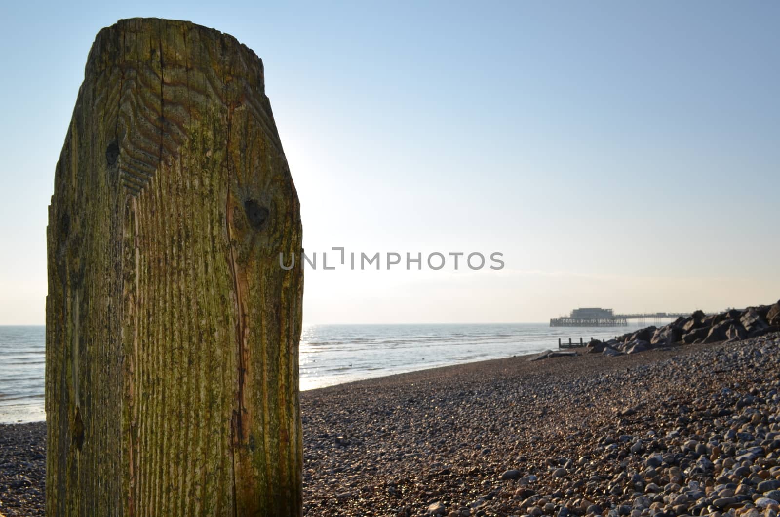 Wooden coastal breakwater along the beach at Worthing,Sussex with the Victorian pier in the background.