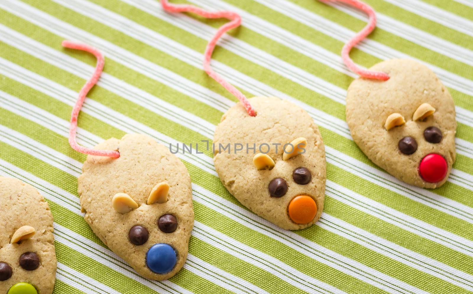 Cookies with mouse shaped and red licorice tail over green striped tablecloth