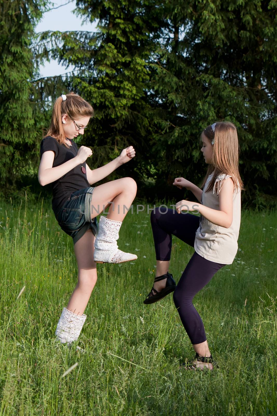 Two teens dancing girls in grass on a meadow