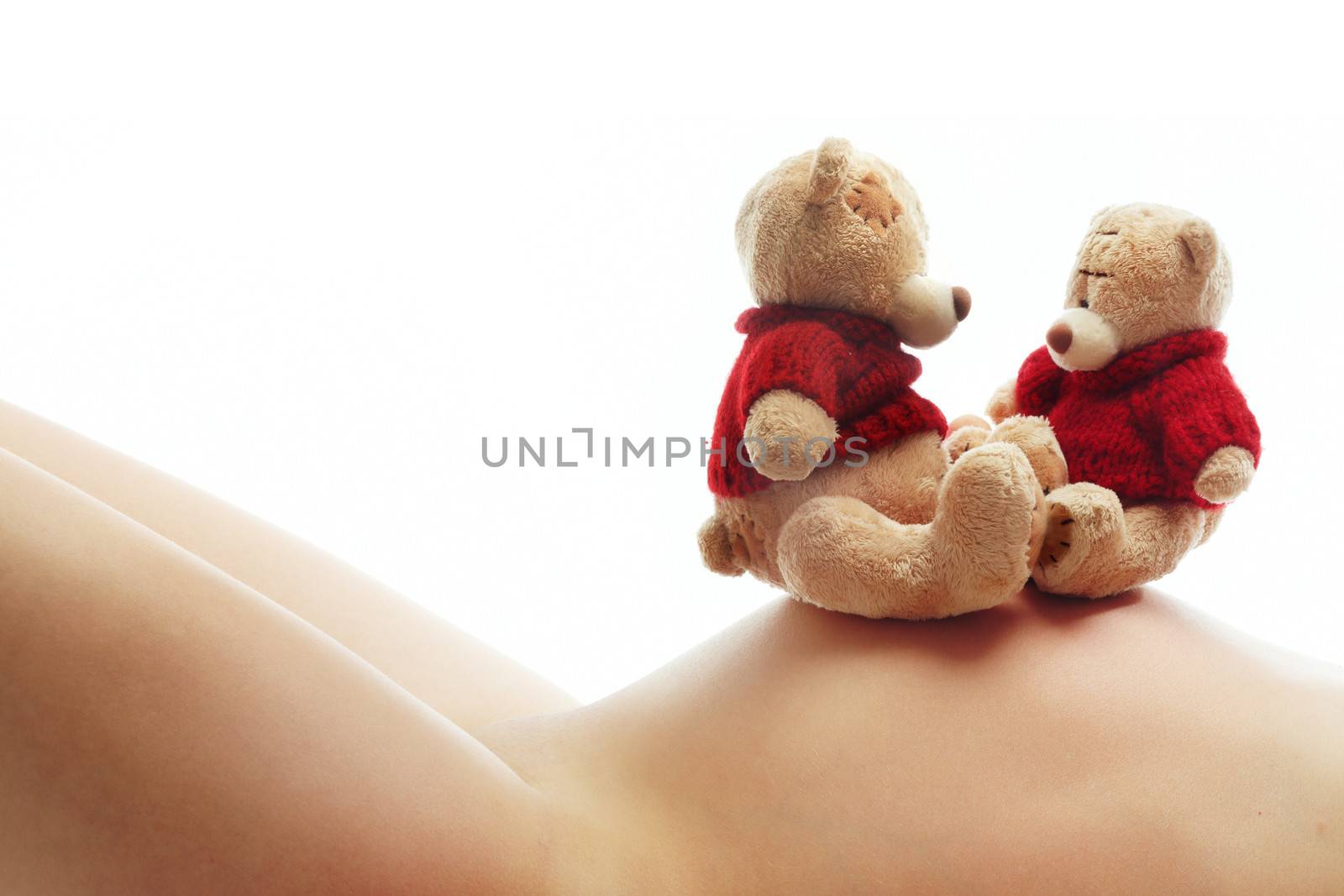 Body of pregnant woman and two teddy bears as a symbol of motherhood