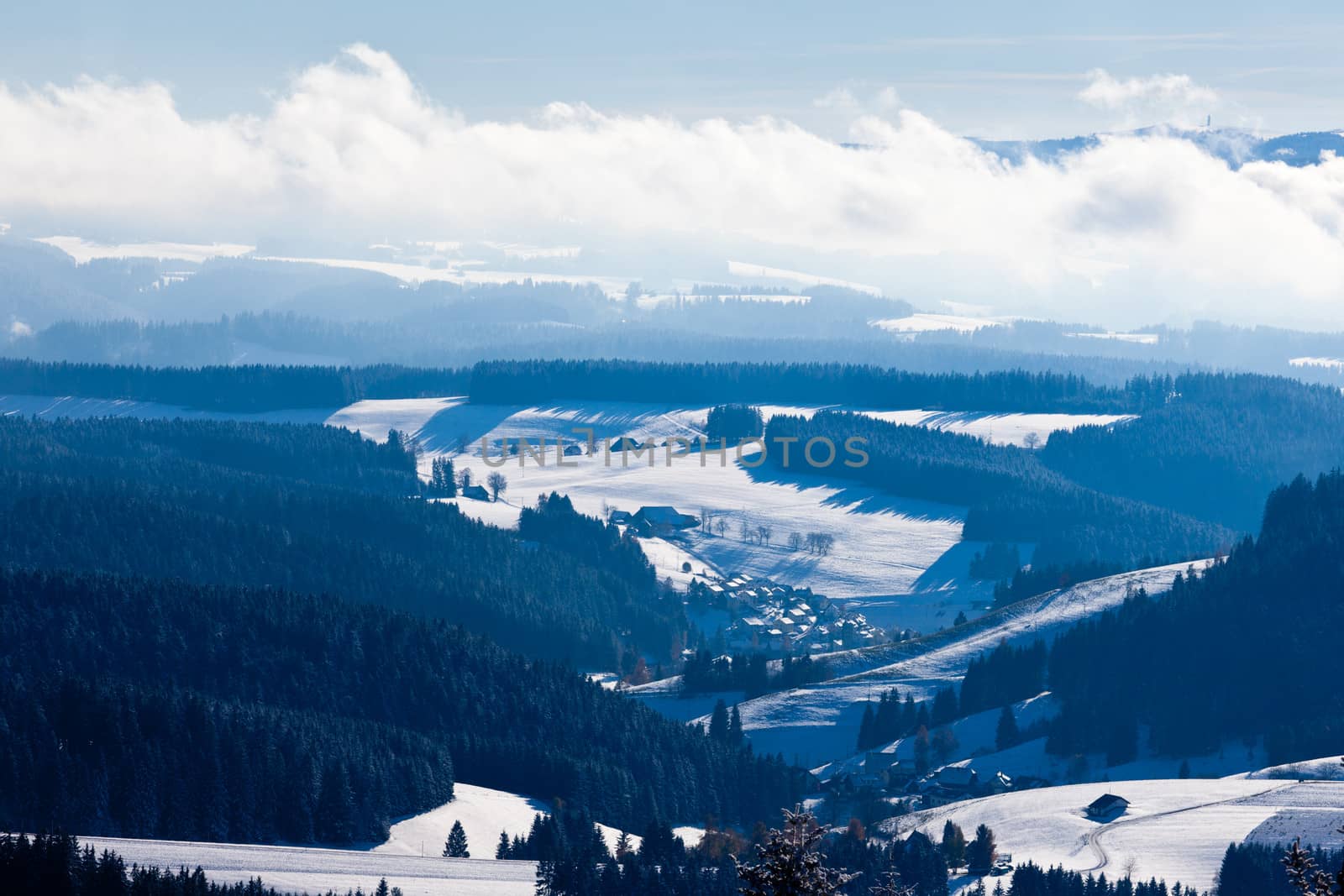 Horizon of foggy mist clouds in snowy winter Black Forest village valley landscape, rural Germany, Europe