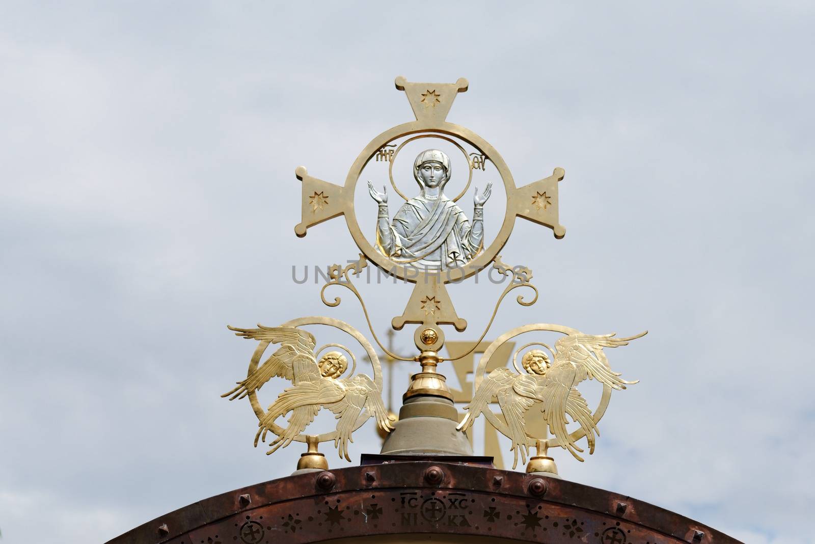 Cross on Orthodox church with Mother Mary and two angels on cloudy sky background