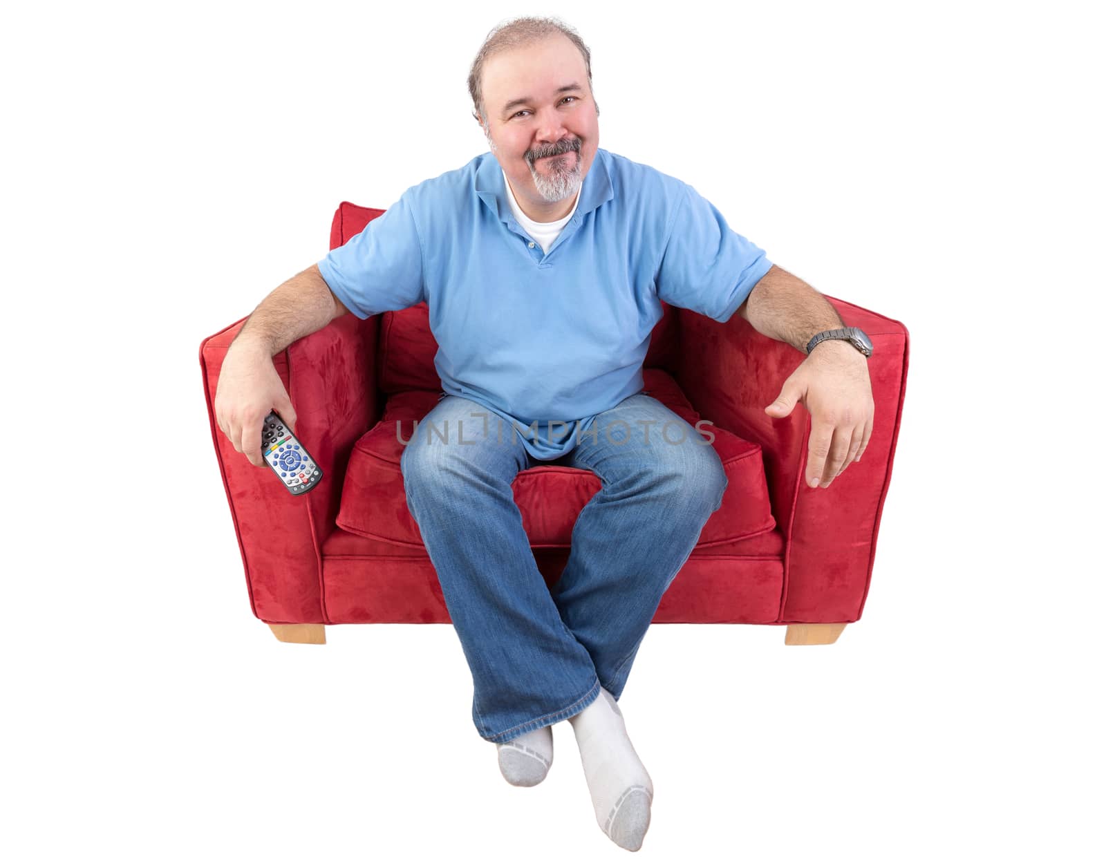 Man sitting in a comfortable armchair with a remote control and a bored expression as he watches something on television that he has seen before