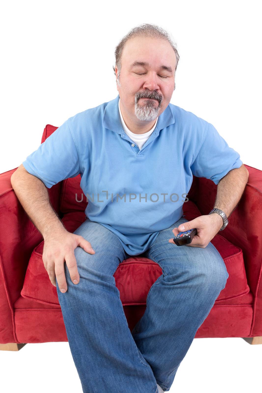 Middle-aged man with a beard holding remote control in his hand closing his eyes in resignation at something on the television isolated on white