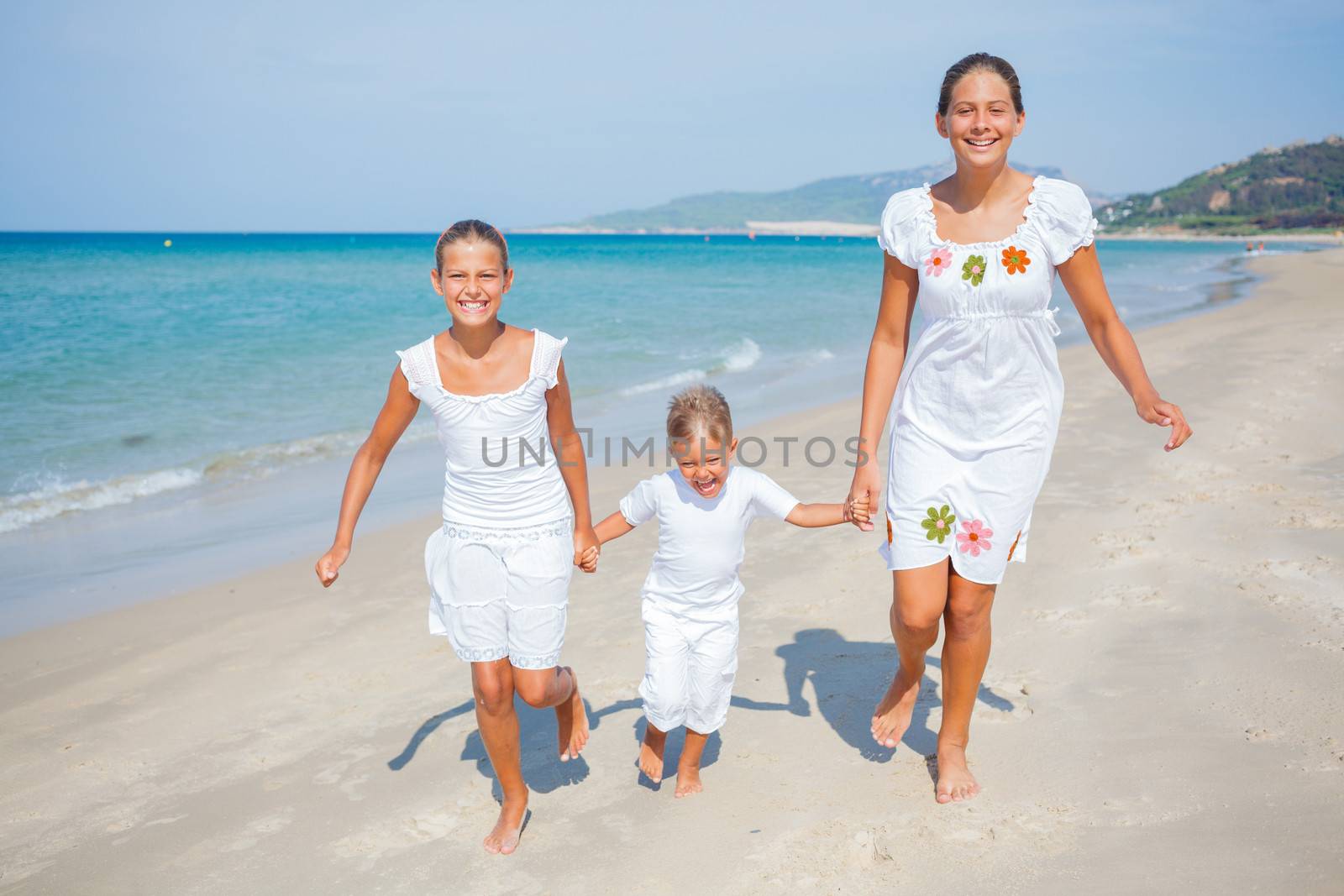 Adorable happy boy and girls running on beach vacation