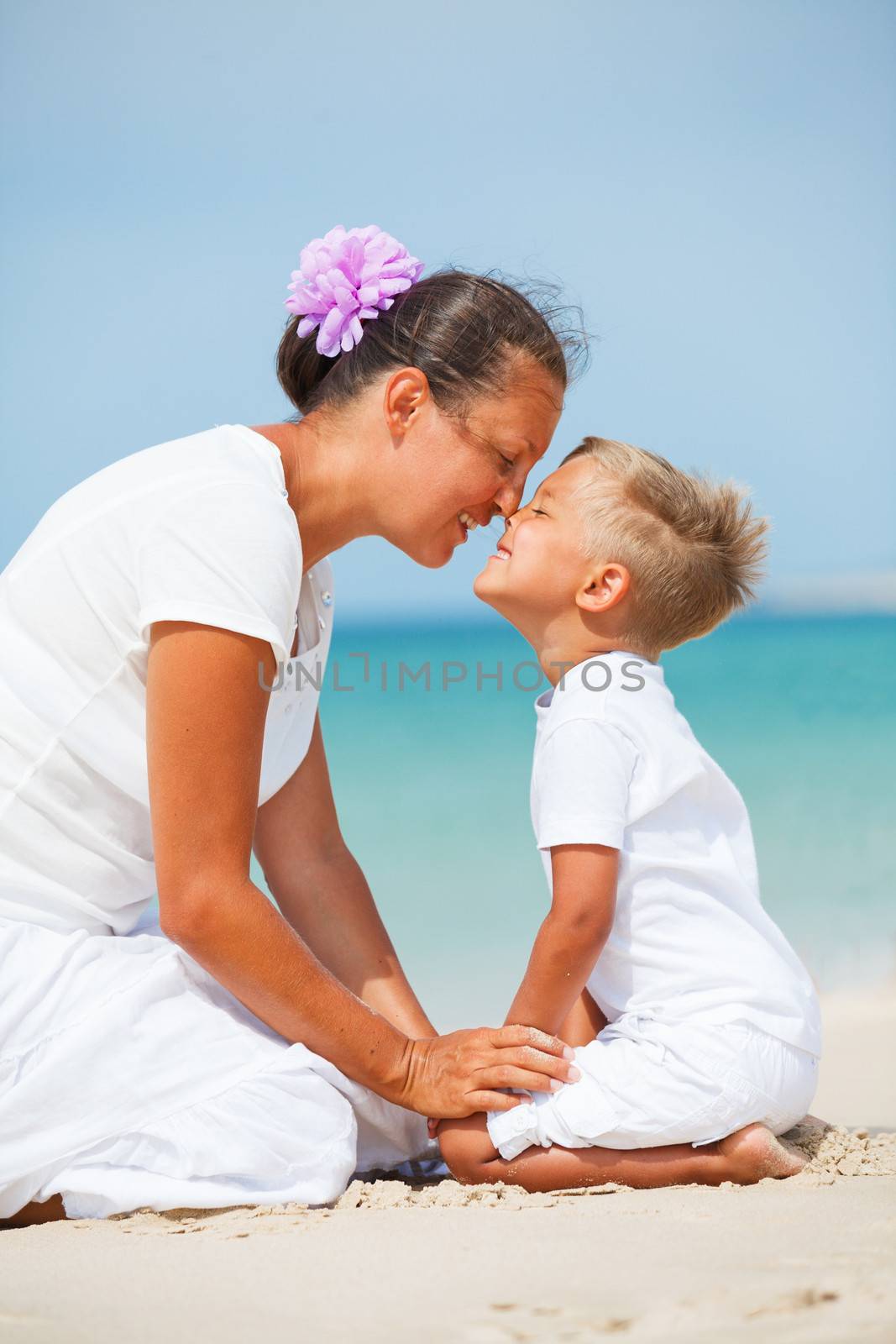 Mother and son having fun on the beach by maxoliki