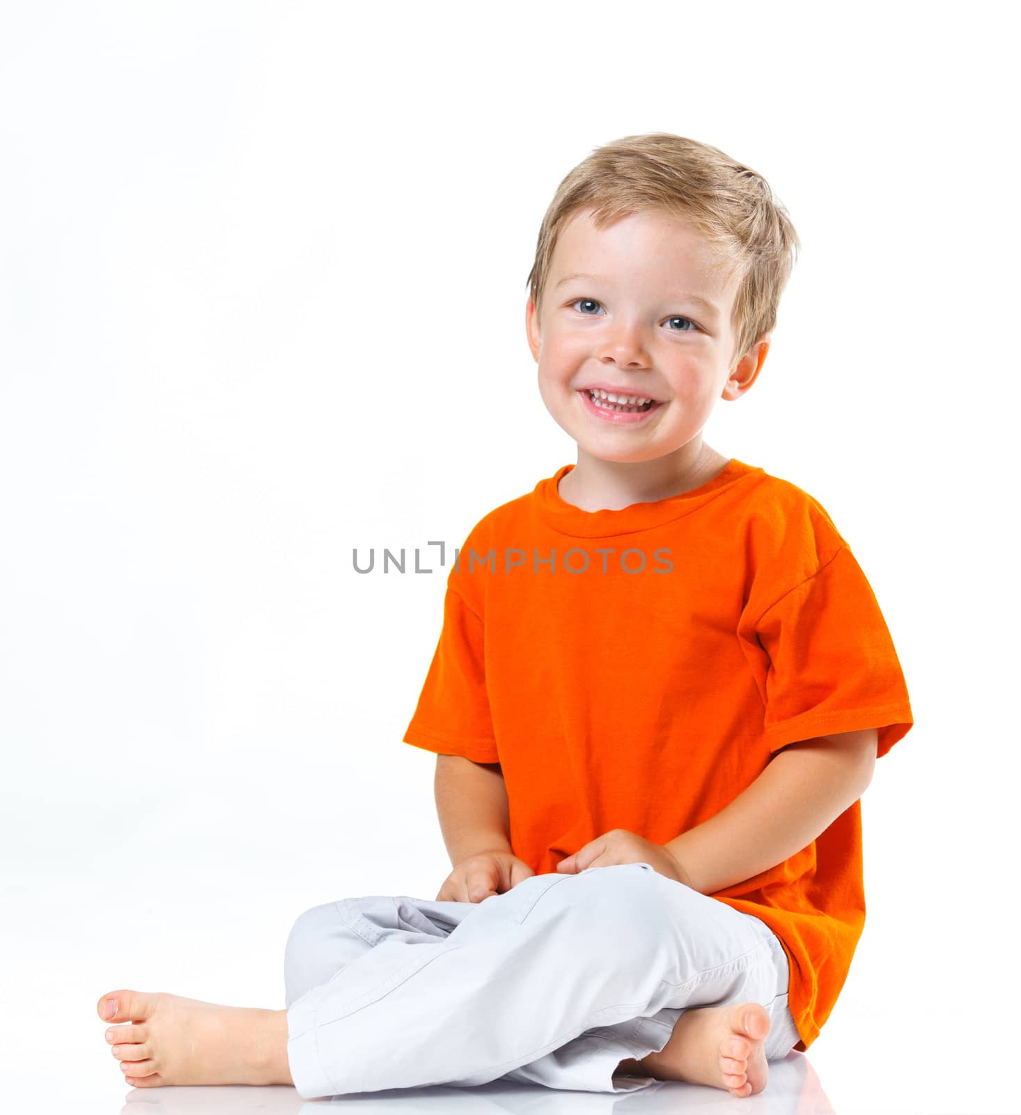Adorable happy boy sitting on the floor in studio. Isolated of white background.